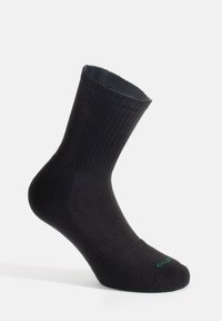 Calcetín negro con textura acanalada, de altura hasta el tobillo y con puntera reforzada. Presenta un logotipo verde en la puntera. Fabricado con material suave y duradero.