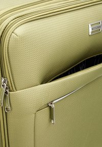 Valigia rigida di colore verde chiaro con finitura testurizzata. Dotata di una tasca con zip e accessori in argento, incluso il tag del marchio.