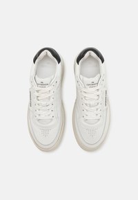 Weisse Leder-Sneaker mit schwarzem Akzent an der Ferse, perforierten Zehen und weissen Schnürsenkeln. Mit Logo auf der Zunge und an der Seite.