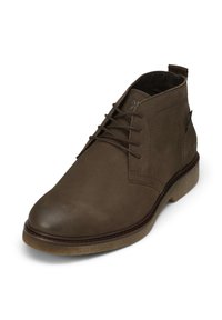 Brązowe skórzane buty chukka z gładką powierzchnią, z okrągłymi sznurówkami, noskiem oraz teksturowaną gumową podeszwą. Krótka wysokość kostki.