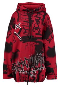 Punainen ja musta ylisuurikokoinen huppari, jossa on graffitityylisiä printtejä, naru-huppu ja elastinen helma, jossa on kontrastiväristä valkoista tekstityötä.