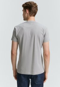 Camiseta gris de manga corta con cuello redondo, hecha de material de algodón suave, con un diseño liso sin patrones ni acentos.