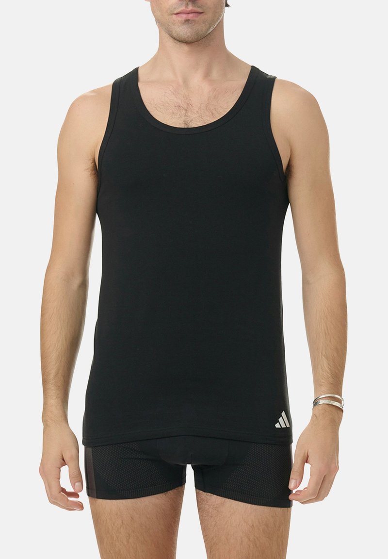 Black tank top made of cotton, featuring a round neckline and Adidas logo on the lower left. Sleeveless design with a fitted cut.