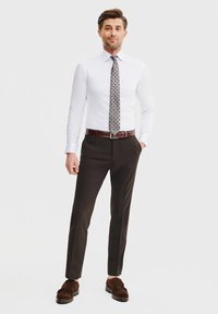 Biała koszula z długim rękawem, wzorzysty ciemny krawat, brązowe spodnie i brązowe zamszowe buty. Prosty design; dopasowany krój; gładka tekstura.