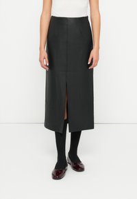 Svart skinn midi skjørt med en frontslit, jevn tekstur og en tettsittende design, kombinert med svarte sokker og burgunder leiligheter.