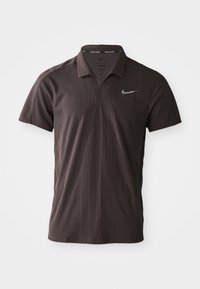 Polo Nike marron foncé à manches courtes avec col et logo Nike swoosh blanc sur la poitrine gauche.