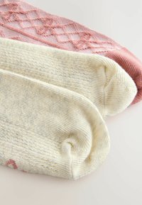 Två par strumpor: en blekgul med texturerad stickning och en ljusrosa med geometriskt mönster, som visar upp olika material.