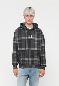 Sudadera de cuadro negro con líneas grises y rojas, que cuenta con un bolsillo canguro y capucha con cordón. Logotipo "GAP" en blanco en el pecho.