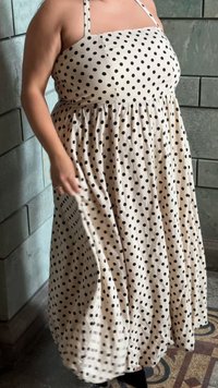 Robe midi à pois en crème avec des taches noires, dotée de fines bretelles, d'un corsage ajusté et d'une jupe fluide. Tissu en coton lisse.