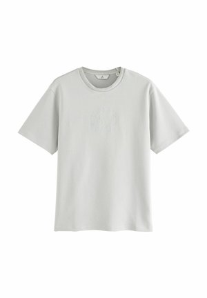 Halluxhallane halli t-särk, millel on ümmargune kaelus, lühikesed varrukad ja tekstuurne ringikujuline logo disain keskel. Pehmest, kergest kangast.