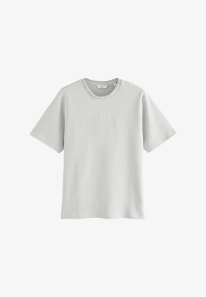 Szara bawełniana koszulka z okrągłym dekoltem, krótkimi rękawami oraz teksturowanym okrągłym logo na środku. Miękka, lekka tkanina.