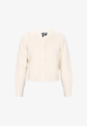 Cardigan court en crème, avec une texture douce et duveteuse. Il a un col rond, des manches longues et sept boutons sur le devant.