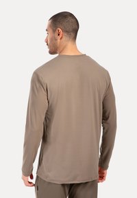 Langarmshirt in erdigem Braun, aus glattem Stoff gefertigt. Verfügt über einen klassischen Rundhalsausschnitt und einen geraden Saum, ohne sichtbare Muster.