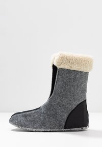 Botte en feutre gris avec un accent en cuir noir, dotée d'un col en fausse fourrure beige pelucheux. Forme svelte avec une texture lisse et un détail de couture.