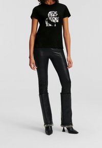 Black short-sleeve t-shirt with a silver sequined graphic design. Paired with shiny black leather leggings and knee-high black heeled boots.