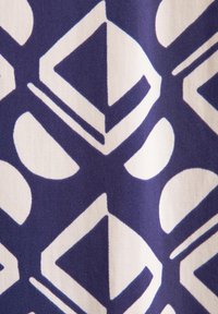 Tessuto blu navy con un motivo geometrico di diamanti e cerchi bianchi. Texture liscia con una finitura morbida e traspirante.