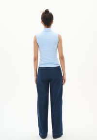 Haut sans manches bleu clair avec un col associé à un jean foncé à jambes larges, présentant un design épuré et une coupe droite.