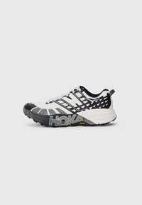 Chaussure de course noir et blanc avec tige en mesh texturé, semelle à motifs et logo "HOKA". Présente un intermédiaire amortissant et une languette.