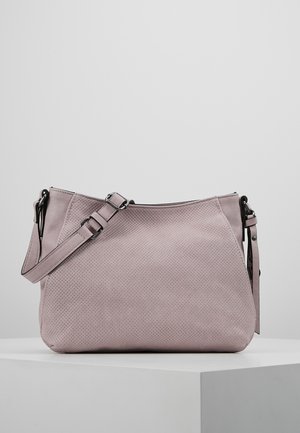 Sac bandoulière mauve clair avec texture perforée, sangle réglable, fermeture éclair et ferrures métalliques noires sur un piédestal blanc.