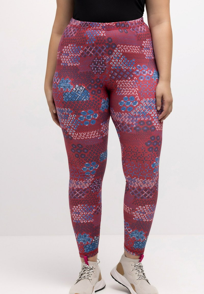 Leggings con un patrón en rojo y azul que presenta formas geométricas y diseños florales. El material es elástico y tiene una cinturilla alta.