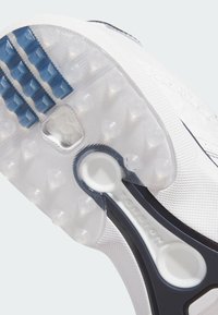 Schuhsohle mit transparentem Gummidesign, blauen Noppen, strukturiertem weißem Material und einem runden weißen Torsionselement.