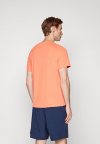 Kortærmet t-shirt i strålende koralfarve, lavet af glat stof. Har en klassisk rund halsudskæring, med en afslappet pasform og sømdetaljer.