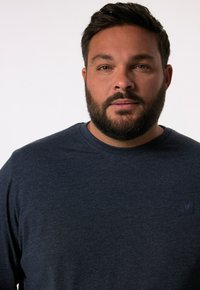 Námořnická modrá košile s dlouhým rukávem vyrobená z jemné strukturované látky; obsahuje decentní logo na levé části hrudi.