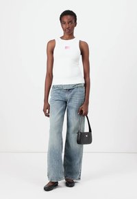 Weißes ärmelloses Tanktop mit kleinem pinken Logo, ausgebleichte blaue weite Jeans, schwarze Handtasche und schwarze Schuhe. Glatte Textur überall.