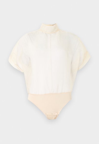 Blouse blanche transparente à manches courtes avec col montant et body beige intégré doté de fermetures pressionnées à l'entrejambe.