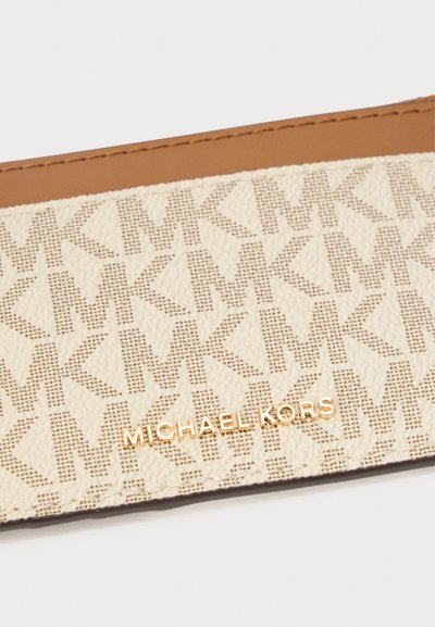 Portefeuille Michael Kors avec une texture crème à motifs comprenant des logos MK entrelacés, accentué par des lettres dorées de la marque et une bordure en cuir marron.