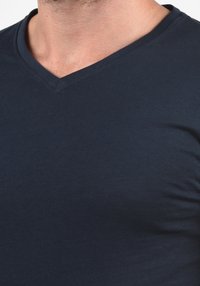 Marineblaues V-Ausschnitt-T-Shirt aus weicher Baumwolle, figurbetontes Design, glatte Textur, mit feiner Naht entlang des Halsausschnitts und Saums.