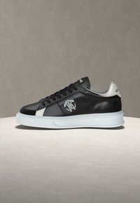 Μαύρο δερμάτινο αθλητικό παπούτσι με λευκή σόλα, σχέδιο με κορδόνια, λευκό λογότυπο στο πλάι και λευκή ετικέτα στη φτέρνα με διακριτικό της μάρκας.