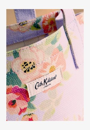 Virágmintás szövet bevásárlótáska varrott fogantyúkkal és egy fehér címkével az elején, amelyen a "Cath Kidston London" felirat olvasható.