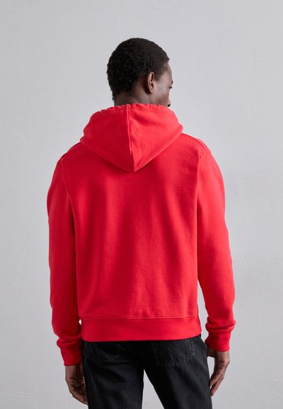 Hoodie rouge avec une capuche à cordon, des poignets et un ourlet ribbed. Matériau en coton lisse avec une coupe décontractée. Pas de motifs ou de logos visibles.