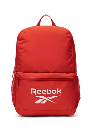 Czerwony plecak Reebok z przednią kieszenią na zamek, bocznymi kieszeniami z siatki oraz górnym uchwytem do przenoszenia. Na przedniej kieszeni nadrukowano biały logo Reebok.