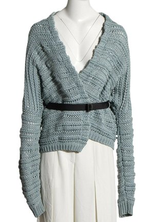 Pull court en maille épaisse bleu clair avec manches longues et col en V profond, associé à une ceinture noire et un bas blanc.