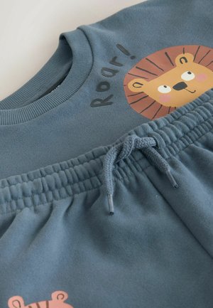 Blue cotton sweatshirt with a lion graphic and "Roar!" text; matching drawstring shorts with a gathered waistband and soft texture.