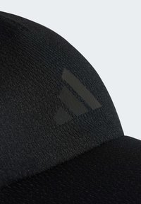 Cappellino nero con tessuto liscio e testurizzato. Presenta un logo a tre strisce scuro in rilievo sul davanti. Design aderente senza hardware visibile.