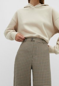 Felpa beige con cappuccio e vestibilità rilassata abbinata a pantaloni a vita alta con motivo camoscio in marrone e crema.