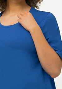 T-shirt à manches courtes en coton bleu uni. Il présente un col en rond et une texture lisse, avec une coupe décontractée et un design simple.