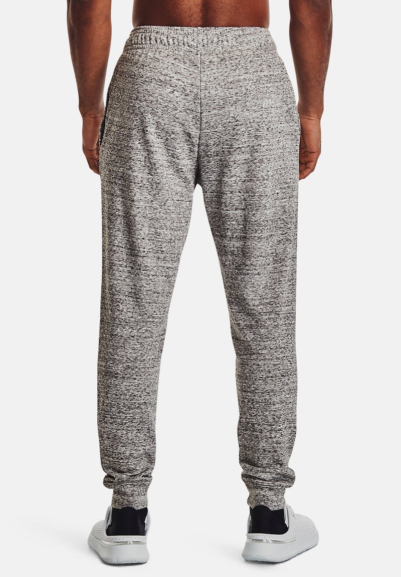 Pantalones de chándal gris jaspeado, hechos de un tejido suave, con cintura elástica, pierna ajustada y bolsillos laterales. Llevados con zapatillas deportivas blancas.