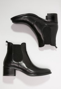 Zwarte leren enkellaarsjes met elastische zijpanelen, een afgeronde neus en een blokhak. Het ontwerp heeft een gladde afwerking en minimalistische accenten.