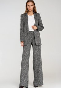 Czarno-biała kratkowana marynarka z dopasowaną kurtką i szerokimi spodniami. Noszona na białej koszulce, charakteryzująca się gładką fakturą.
