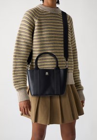 Zwarte leren tote bag met een gestructureerde vorm, dubbele handvatten en een afneembare schouderriem. Voorzien van een verhoogd logo en subtiele stikdetails.