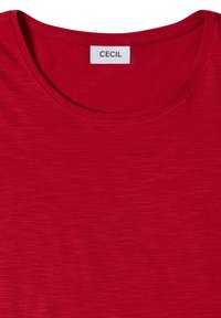 T-shirt rouge à col rond avec une étiquette blanche cousue à l'intérieur du col indiquant le nom de la marque Cecil en lettres noires.
