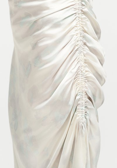 Λευκό ύφασμα με διακριτικό φλοράλ μοτίβο, με κάθετη ρυτιδωτή λεπτομέρεια που δημιουργεί συγκεντρωμένες, υφασματικές πτυχώσεις.