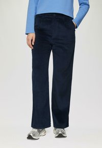Navy corduroy wijde broek met een gestructureerd oppervlak, voorzien van een knoopsluiting aan de voorkant en zijzakken, gecombineerd met zilveren sneakers.