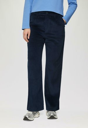 Navy corduroy wijde broek met een gestructureerd oppervlak, voorzien van een knoopsluiting aan de voorkant en zijzakken, gecombineerd met zilveren sneakers.