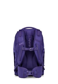 Mochila morada con correas acolchadas para los hombros, respaldo de malla, hebillas ajustables y detalles de logo; presenta un diseño aerodinámico y estructurado.