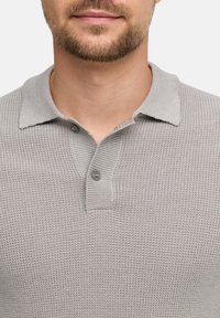 Polo shirt grigio a trama con bottoni. Presenta un design con colletto e un sottile motivo a nido d'ape.